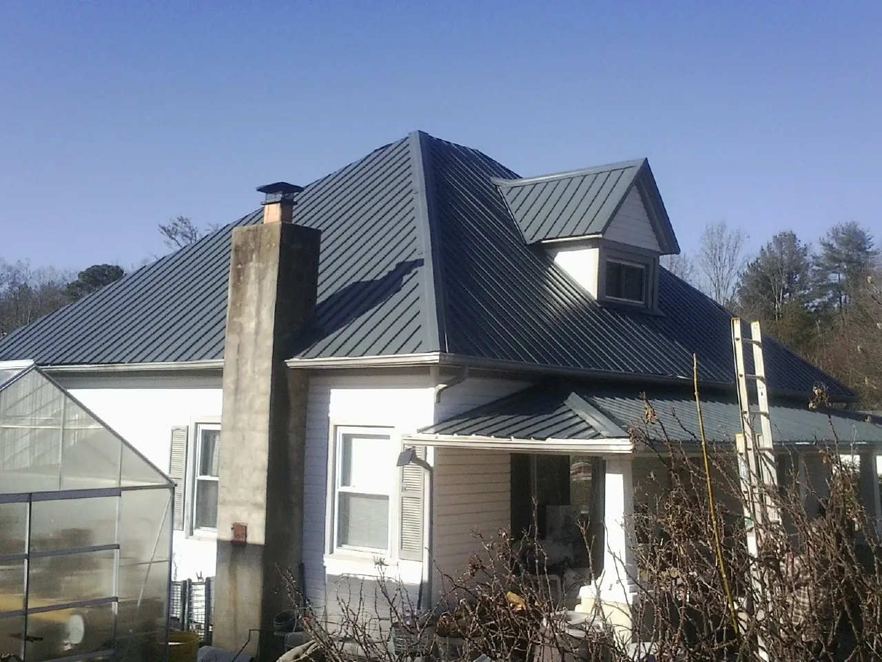 Dark blue standing seam metal roof on a white farmhouse with dormer — Slate & Tile Roof Repair by Roofing Brothers in Oldtown