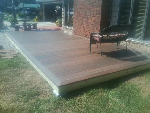New wood deck and wicker chair beside a brick house in Oldtown