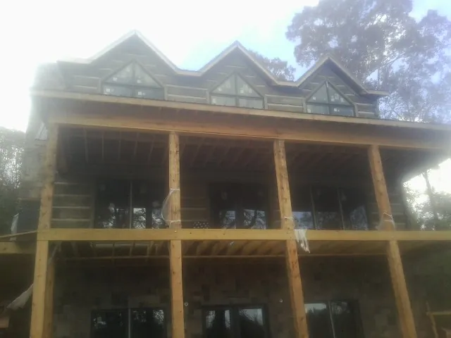 Dormers and porch framing on a large log home under construction — Roof Coating work by our crew in Oldtown