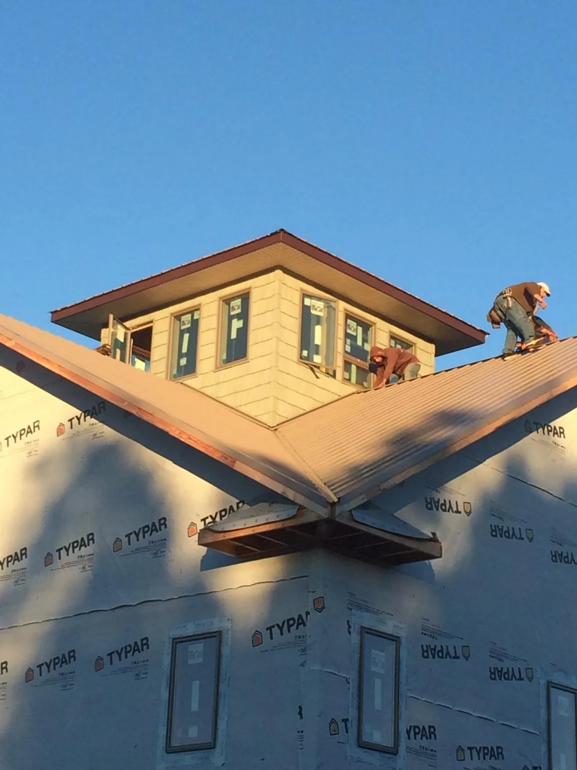 Roofers working around a rooftop cupola on a new metal roof at sunset — Roof Waterproofing in Oldtown by Roofing Brothers